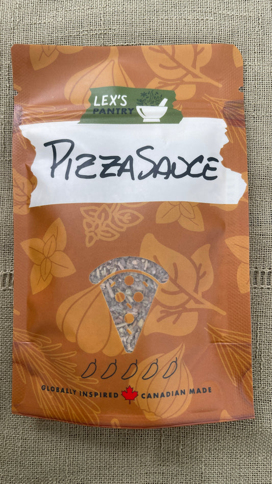 A stand-up pouch of Lex's Pantry Pizza Sauce Spice Blend & Seasoning on a textured green fabric background. The packaging is kraft-brown with herbs and garlic patterning, a white label with 'PIZZASAUCE' written in black marker, and a small pizza slice clear window near the bottom showing the spice inside.