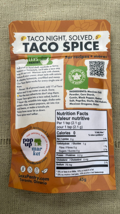 The back of a bag of Lex's Pantry Taco Spice - 'Taco Night, Solved' , shown against a textured green fabric background. The packaging is brown and white with clear labeling of ingredients, nutritional facts, and  an Ontario Made logo