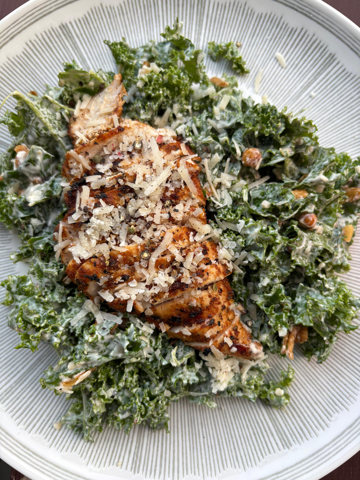 Montreal Red Chicken Salad with kale and croutons on a white plate