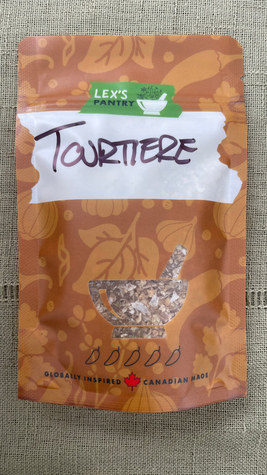 A stand-up pouch of Lex's Pantry Tourtiere Seasoning on a textured green fabric background. The packaging is kraft-brown with herbacious pattern, featuring a white label with 'Tourtiere' written in black script and a clear window showing the seasoning inside.